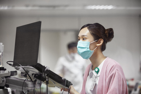 A woman in a medical facemask working with a computer